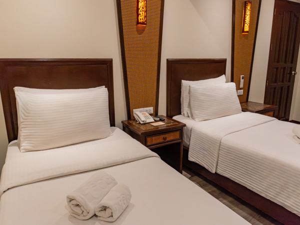 Three-Bedroom Family Suite at Red Coconut: twin beds side by side with white linens and a carved timber headboard.