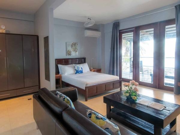 Deluxe Sea View at Reef Beach Resort: bed and sofa in a bright room with louvred doors opening outside.