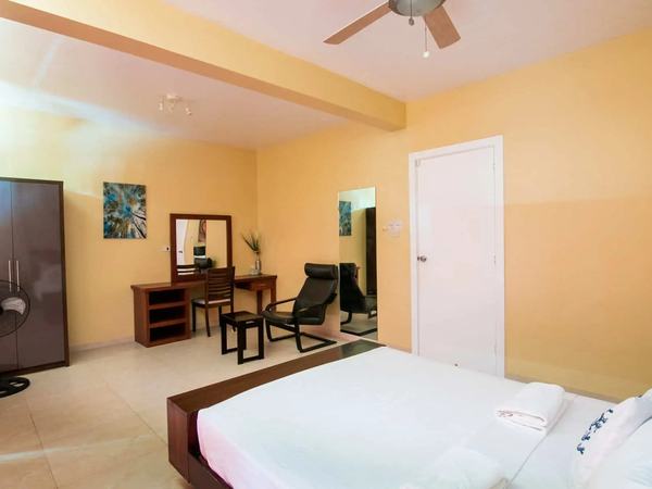 Two Bedroom Suite at Reef Beach Resort: bed with white linens, a desk and chair, and a doorway through to the next room.