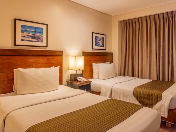 Classic Room at Boracay Sands: two beds with cream and gold runners, framed prints above a timber headboard.