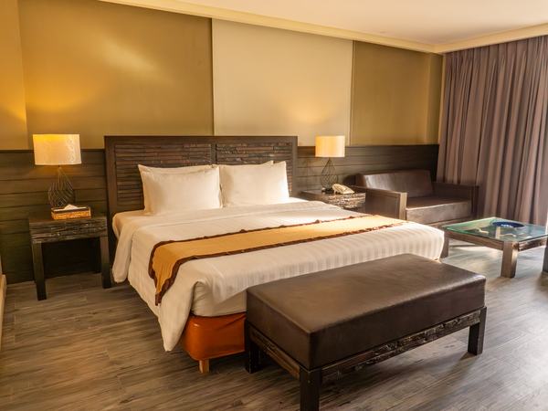 Deluxe Beach View at Boracay Sands: king bed with a padded bench at its foot and a seating nook by the window.