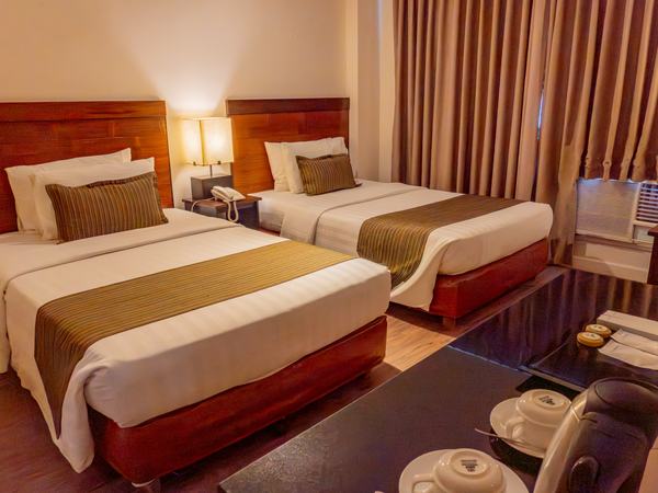 Family Room at Boracay Sands: two large beds side by side with gold runners and a mirrored wall behind.