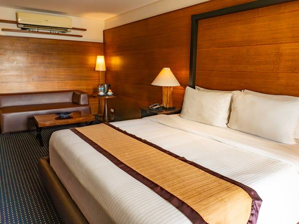 Beachfront Junior Suite at Boracay Sands: king bed with a long timber headboard, lamps either side and a low bench.