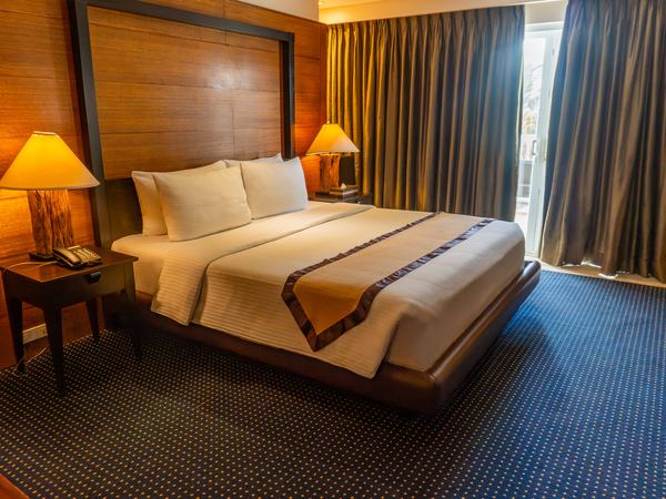 Premier Beach View at Boracay Sands: king bed with a timber headboard and lamps either side, curtains drawn at the window.