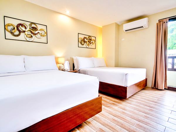 Deluxe Room at Serene La Playa: two queen beds with white linens, framed prints above and a lamp between them.
