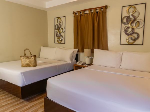 Family Room at Serene La Playa: two queen beds with white linens against a timber headboard wall.